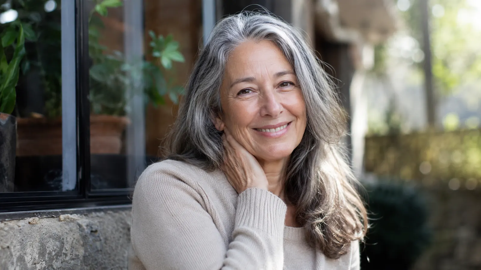 A woman in her sixties outdoors in daylight with visibly hydrated, healthy-looking skin