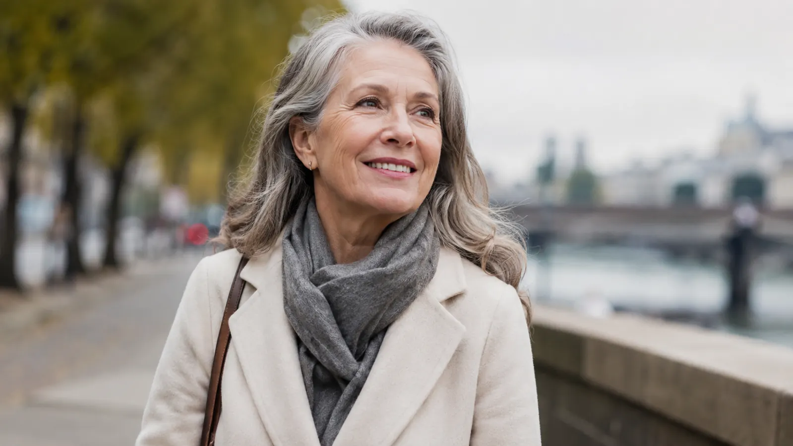 A woman in her sixties smiling outdoors in cool weather, skin visibly comfortable and not tight or flaking