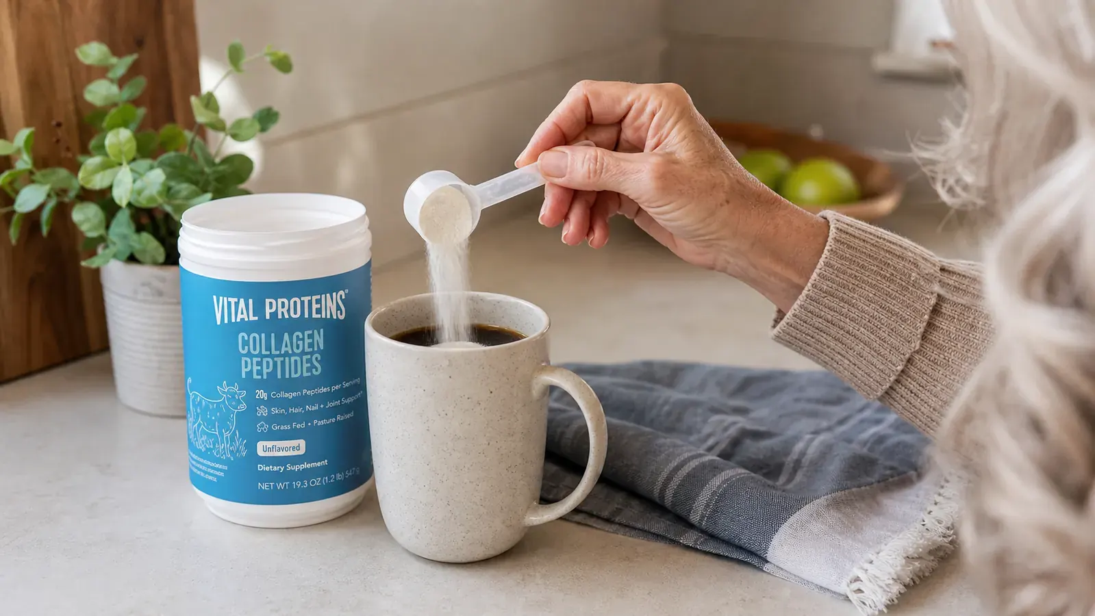 Close-up of a hand scooping Vital Proteins Collagen Peptides powder from the tub into a mug